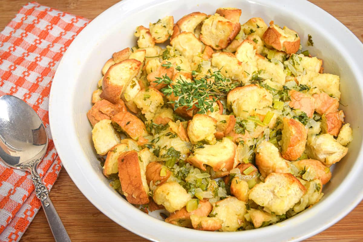 Stuffing with fresh thyme in white bowl and a spoon on the side.