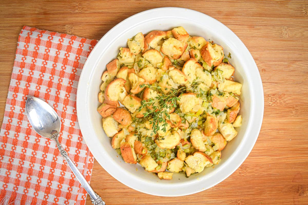 Stuffing with fresh thyme in white bowl and a spoon on the side.