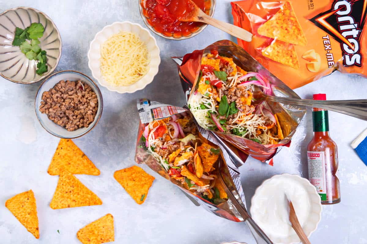 Tacos in small, open Doritos bags and toppings on the side.