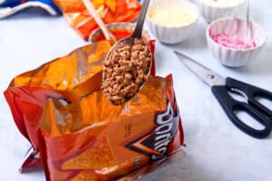 Taco meat on a spoon and 2 small Dorito bags.