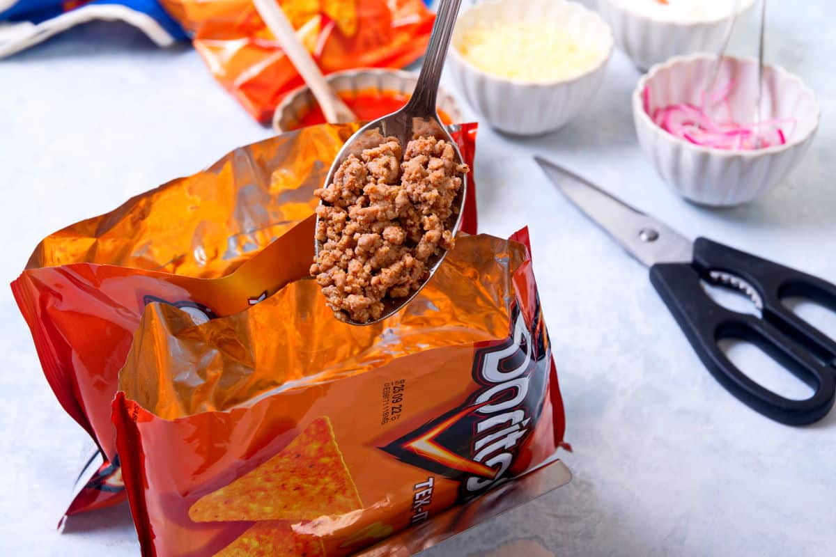 Taco meat on a spoon and 2 small Dorito bags.