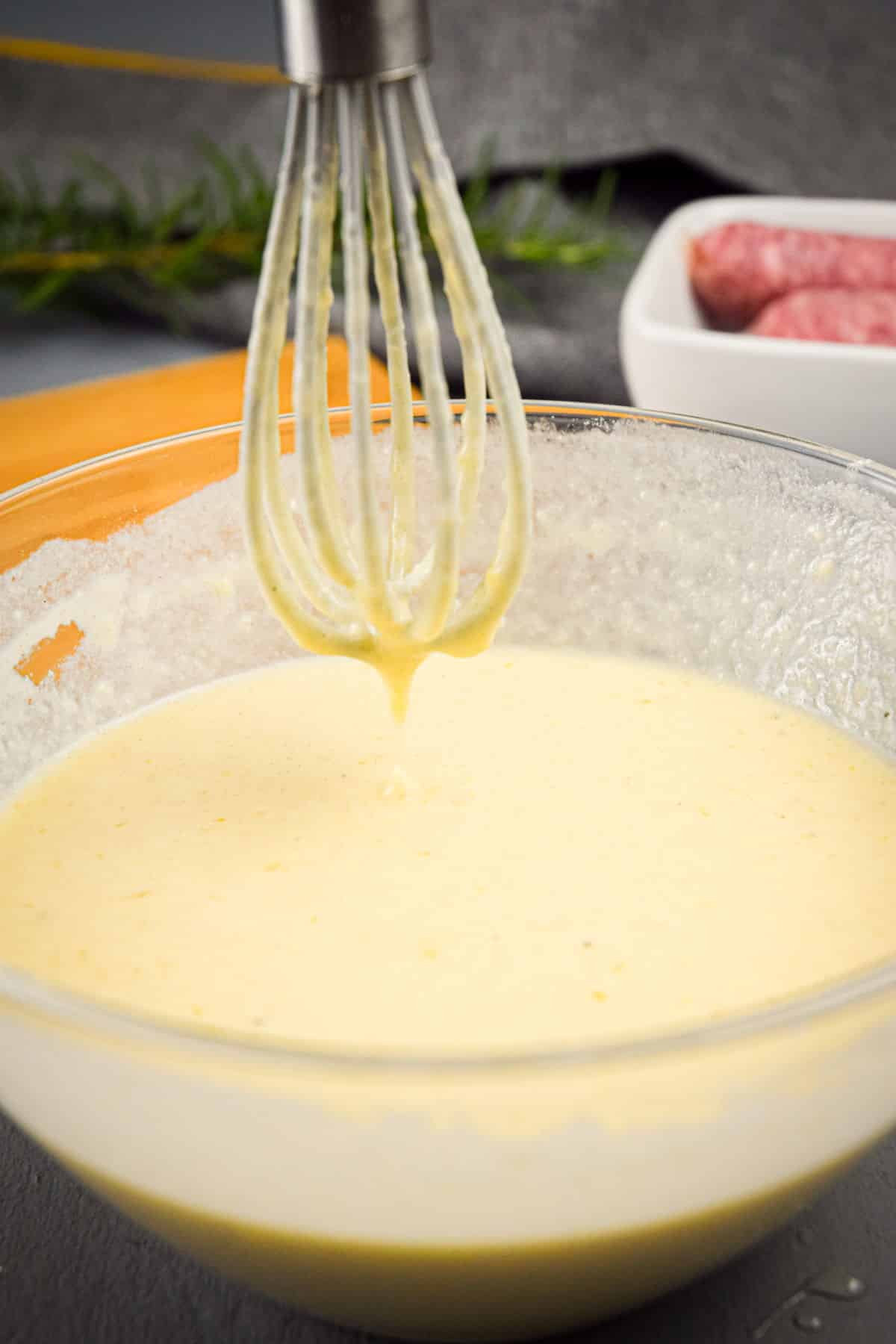 Toad in hole batter in glass bowl with a whisk.