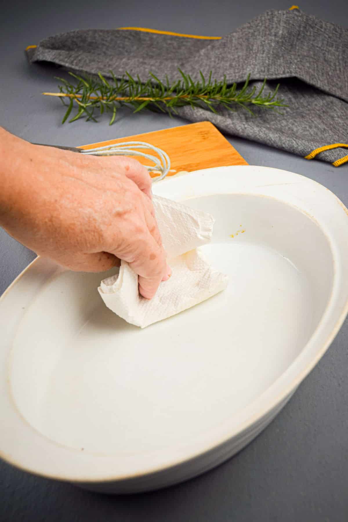 Large casserole dish being wiped with paper towel.