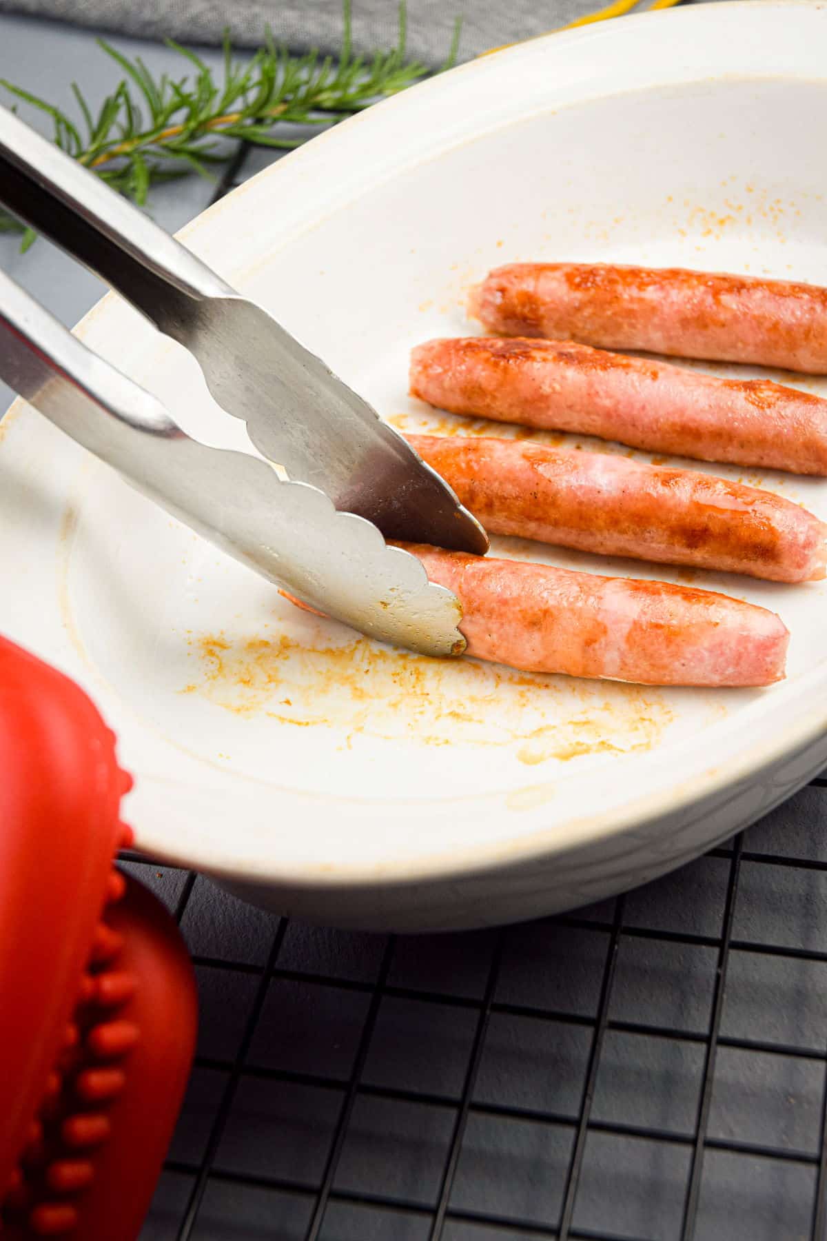 Cooked English pork sausages in white casserole dish.