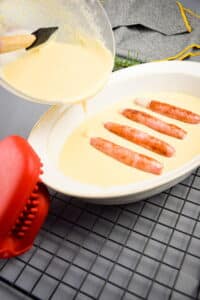 Cooked English pork sausages in white casserole dish with batter.