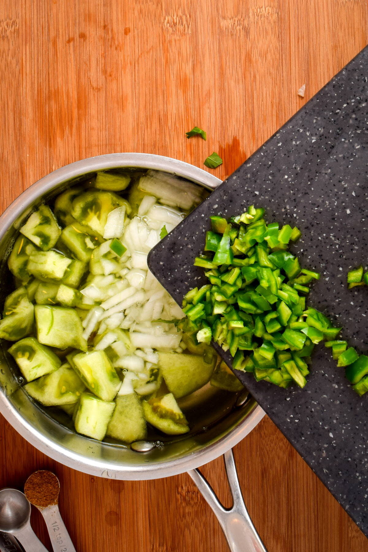 How to Make Tomatillo Salsa_6 Diced green peppers on cutting board over pot of water, onions and tomatillos.