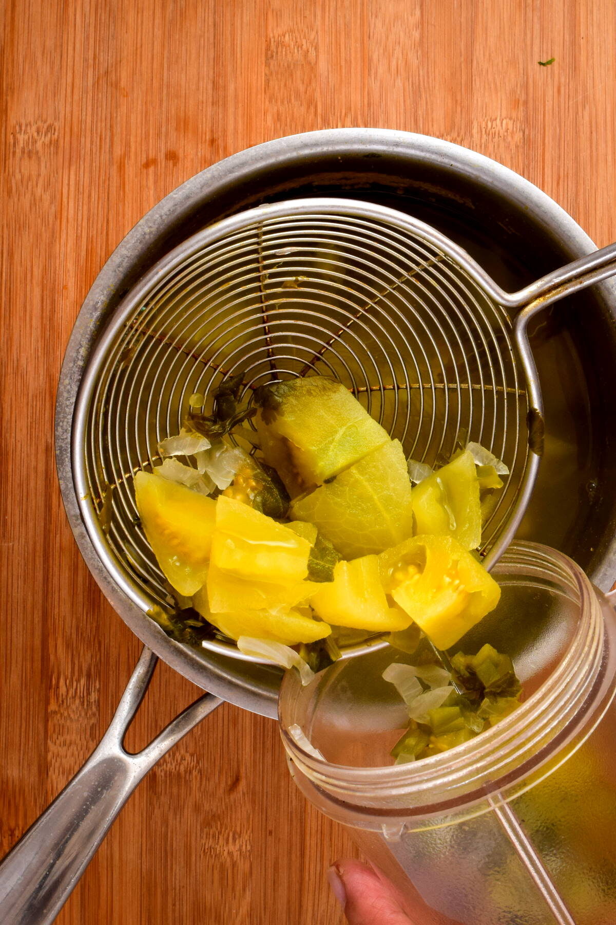 How to Make Tomatillo Salsa_8 Cooked tomatillo salsa ingredients being transferred to a blender jar.