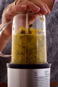 Cooked tomatillo salsa ingredients blended together in a blender.