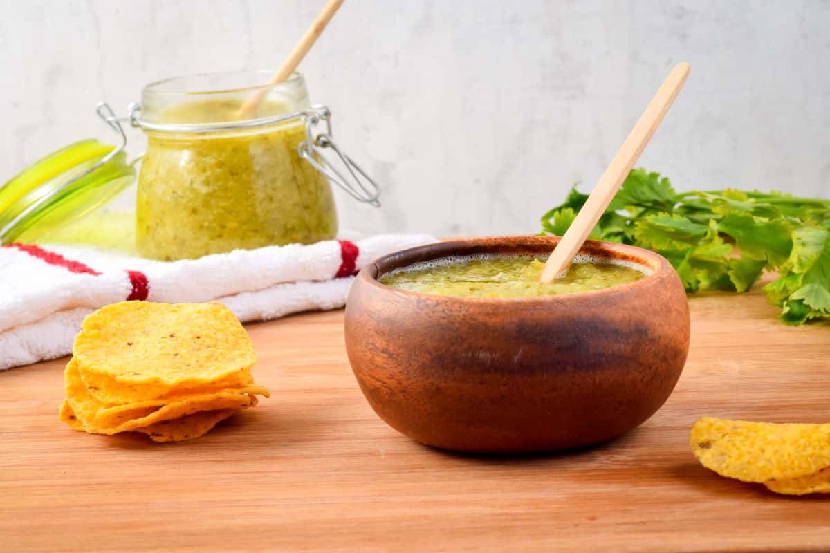 How to Make Tomatillo Salsa_11 A wooden bowl of tomatillo salsa and tortilla chips on the side.