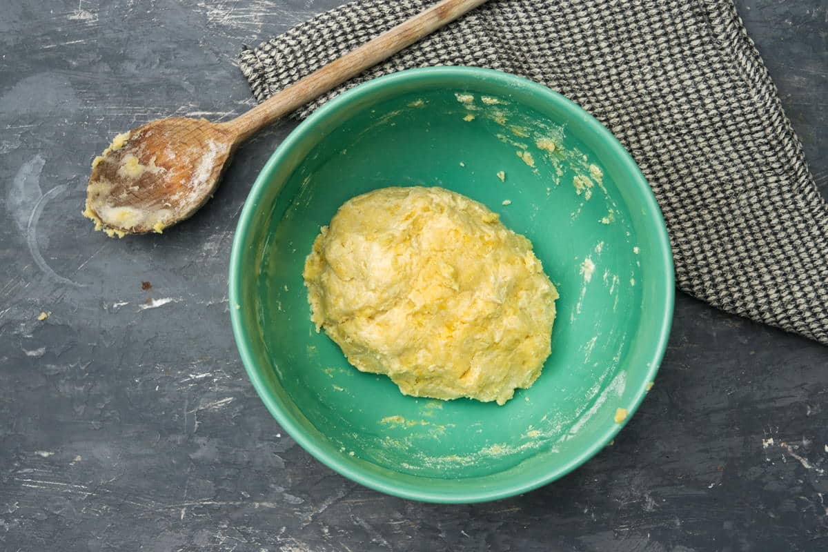 Galette pastry dough in a bowl, wooden spoon on the side.