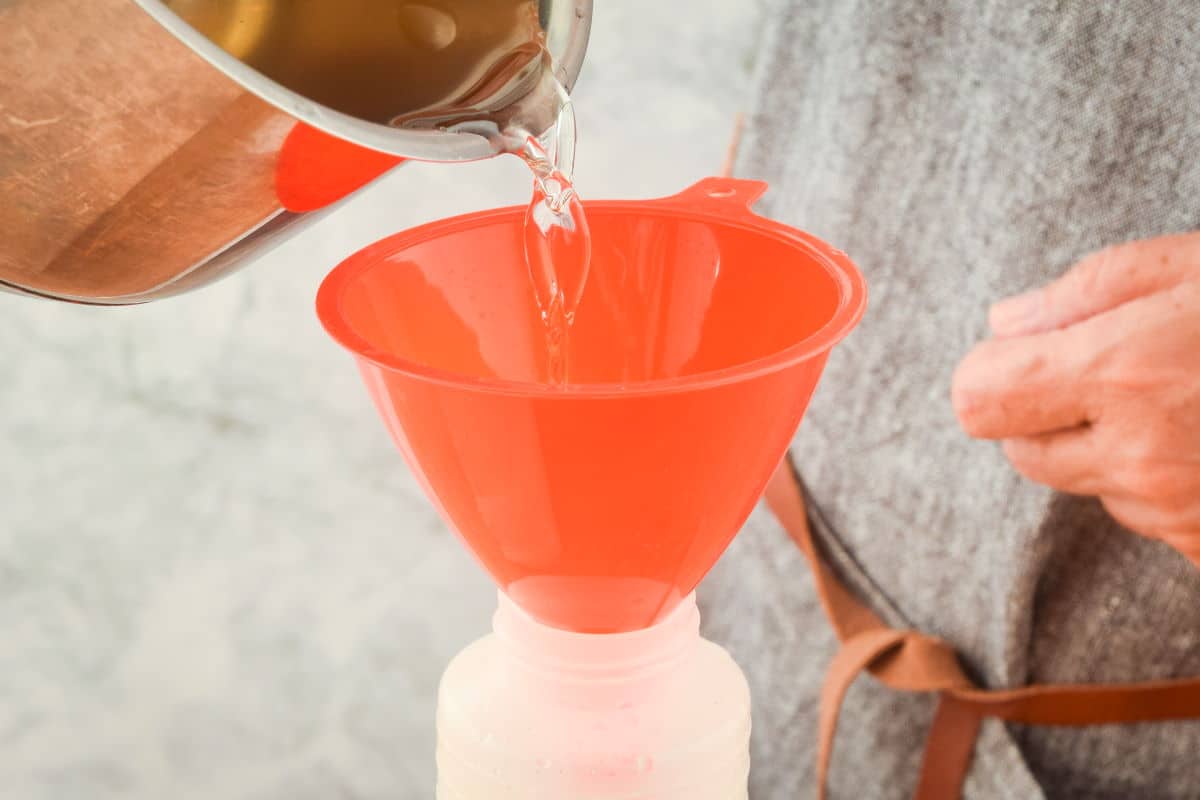 Simple syrup pouring into red funnel.