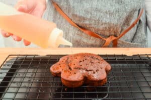 Chocolate cake with holes and a bottle of simple syrup.