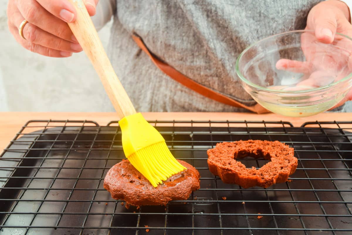 Small chocolate cake sliced in half with simple syrup.