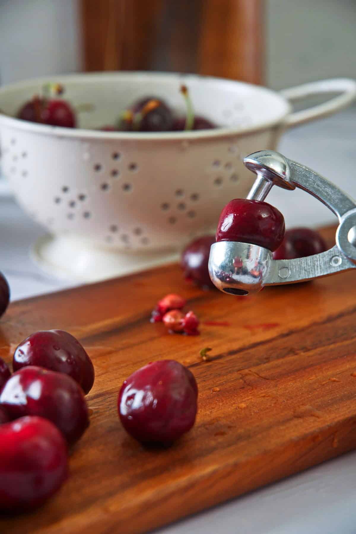 Cherries and cherry pitter on cutting board.