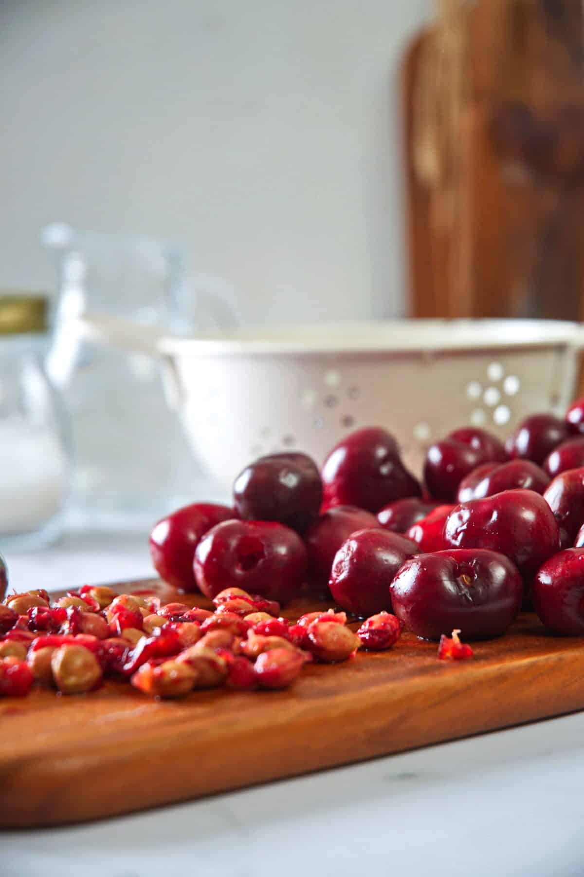Pitted cherries and a cherry pitter on cutting board.