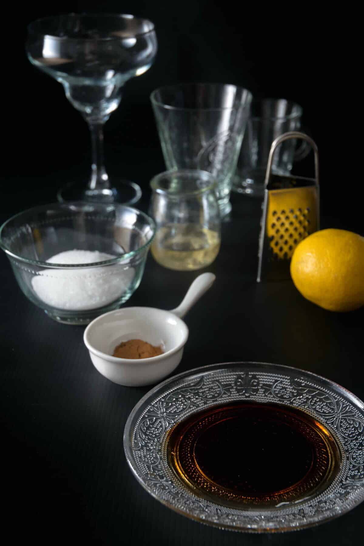 Prepped ingredients and tools for sugar rimming on black background.