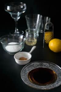 Prepped ingredients and tools for sugar rimming on black background.