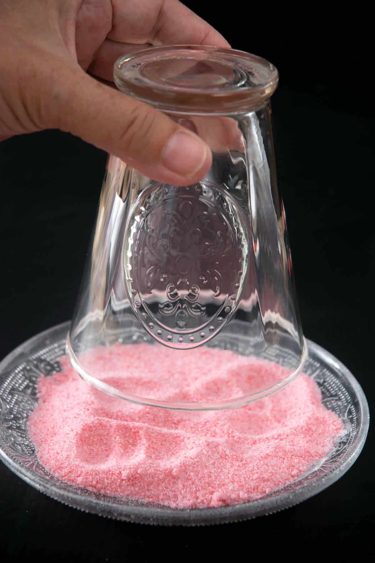 Cocktail glass dipping into pink sugar.