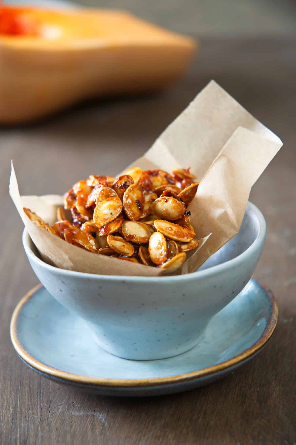 Roasted butternut squash seeds in a small blue bowl.