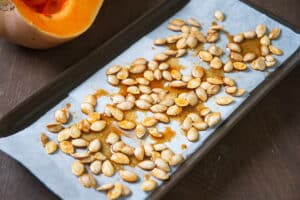 Butternut squash seeds on a parchment paper lined sheet pan.