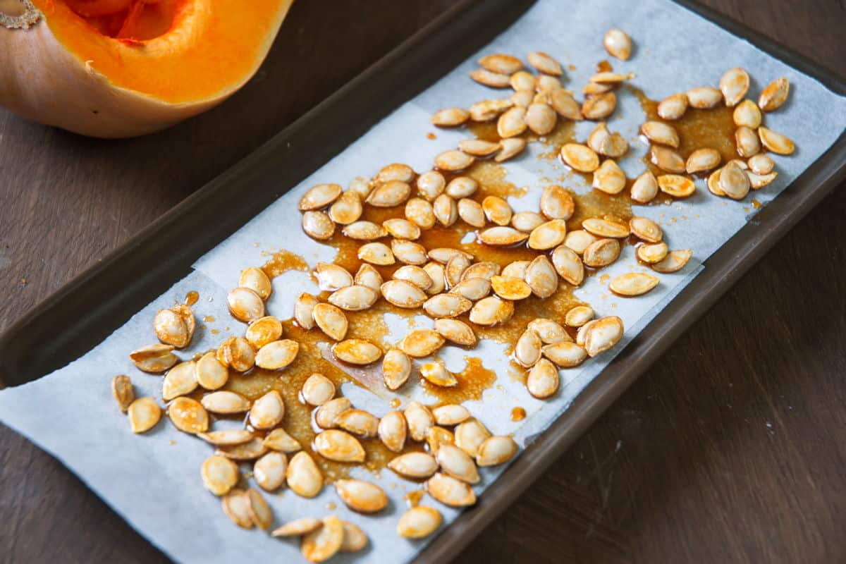 Butternut squash seeds on a parchment paper lined sheet pan.