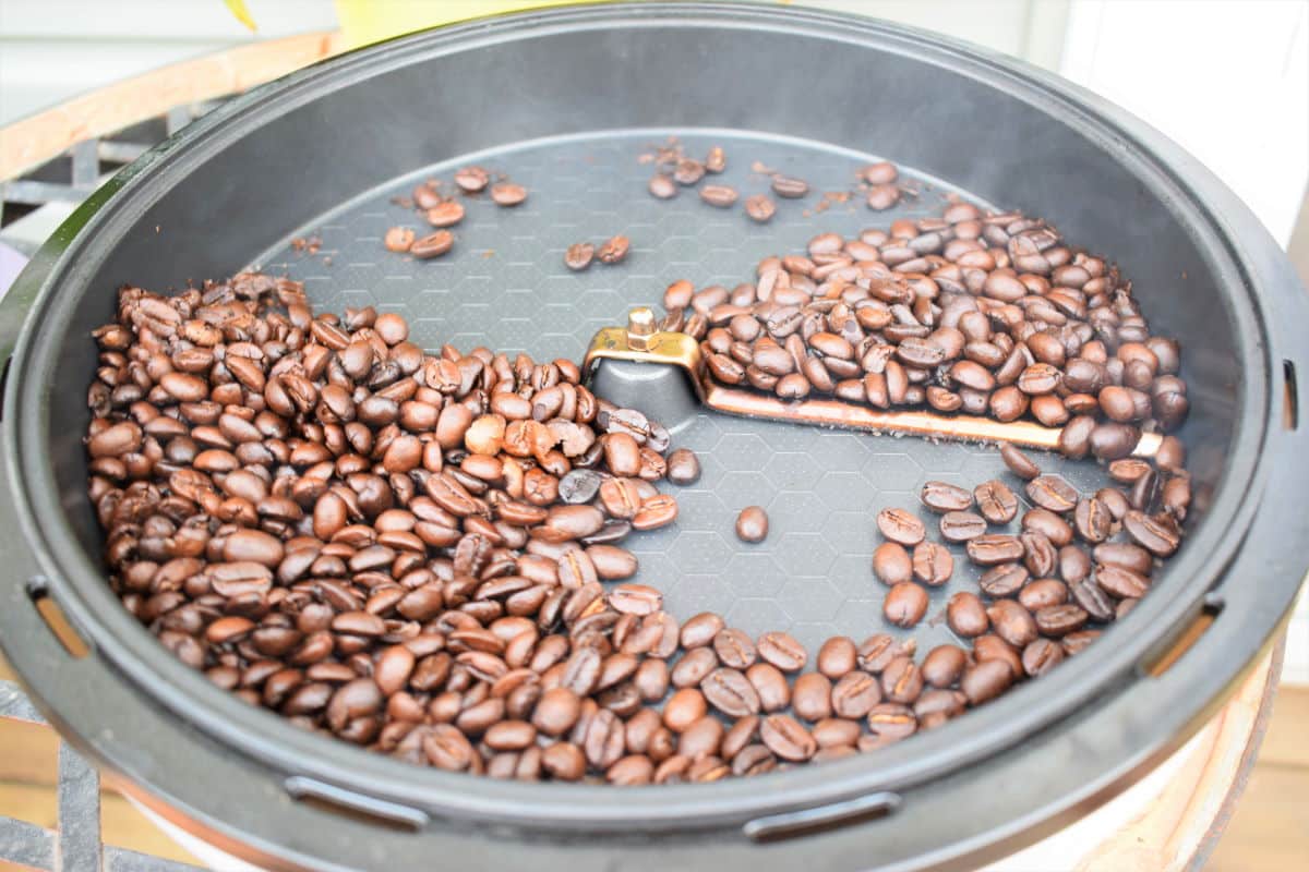 Open coffee roaster with dark coffee beans.