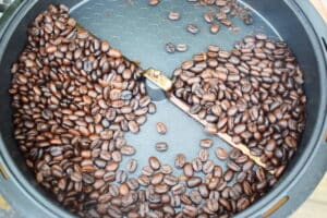 Open coffee roaster with dark coffee beans.