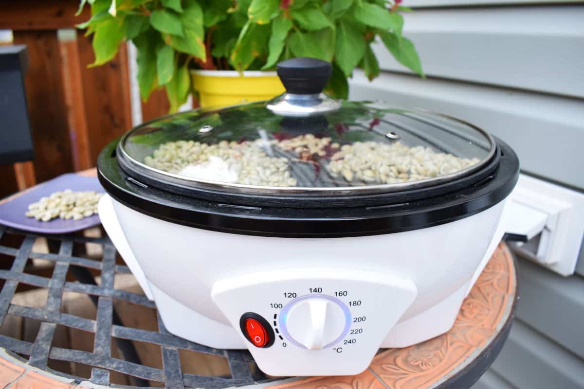 Coffee roaster with raw green coffee beans and a lid on.