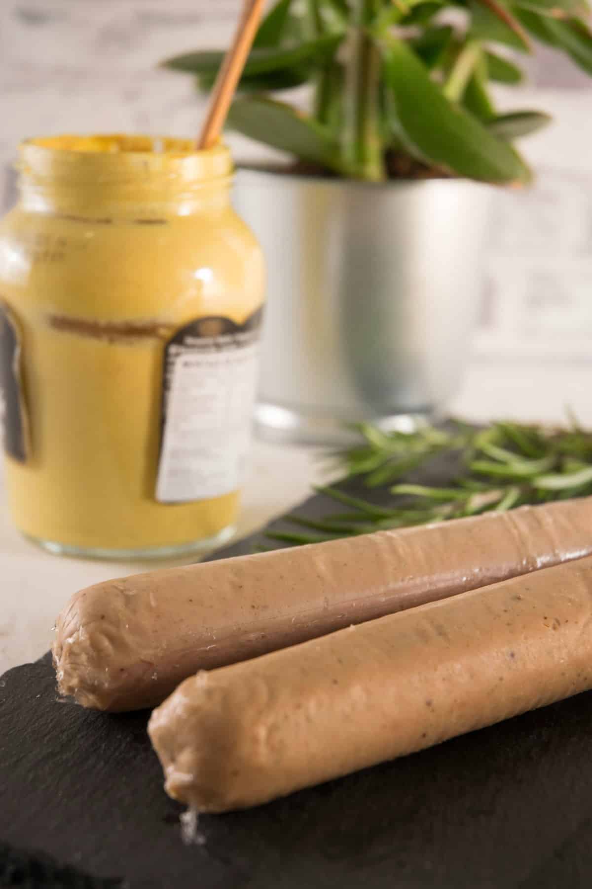 Uncooked bratwurst sausages with German mustard in the background.
