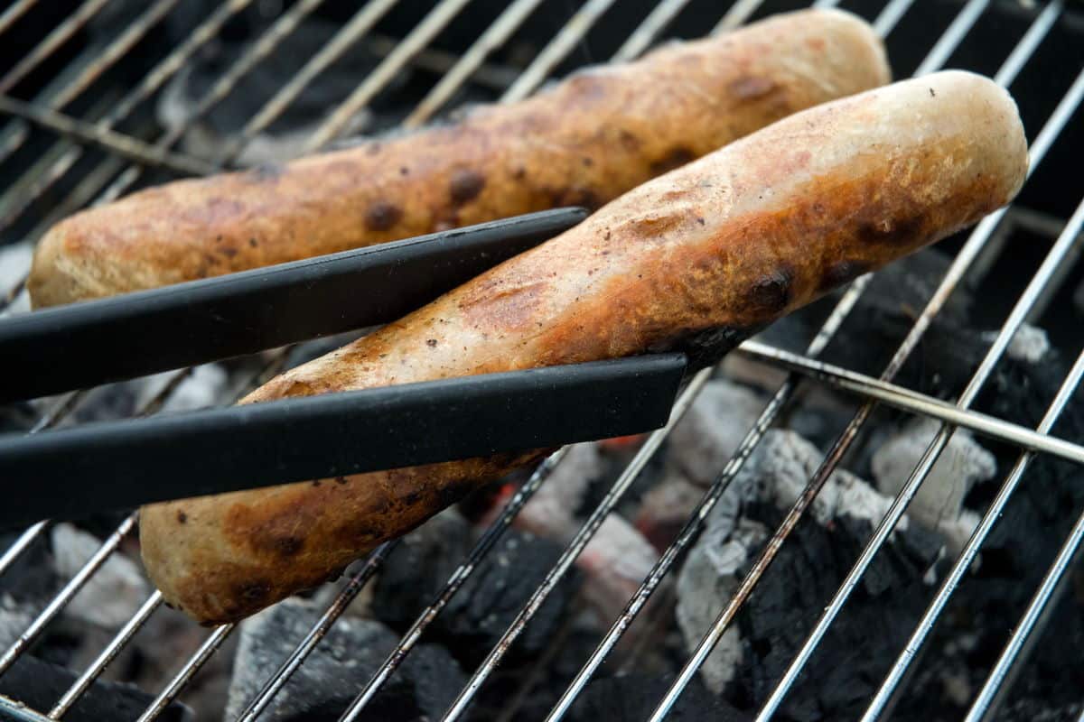 Cooked Bratwurst sausages on the grill getting removed.
