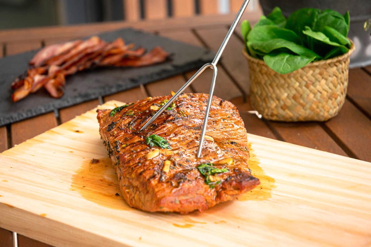 Carne asada on cutting board with meat fork.