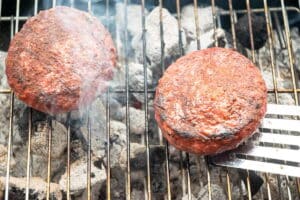 Burger patties on the charcoal grill.