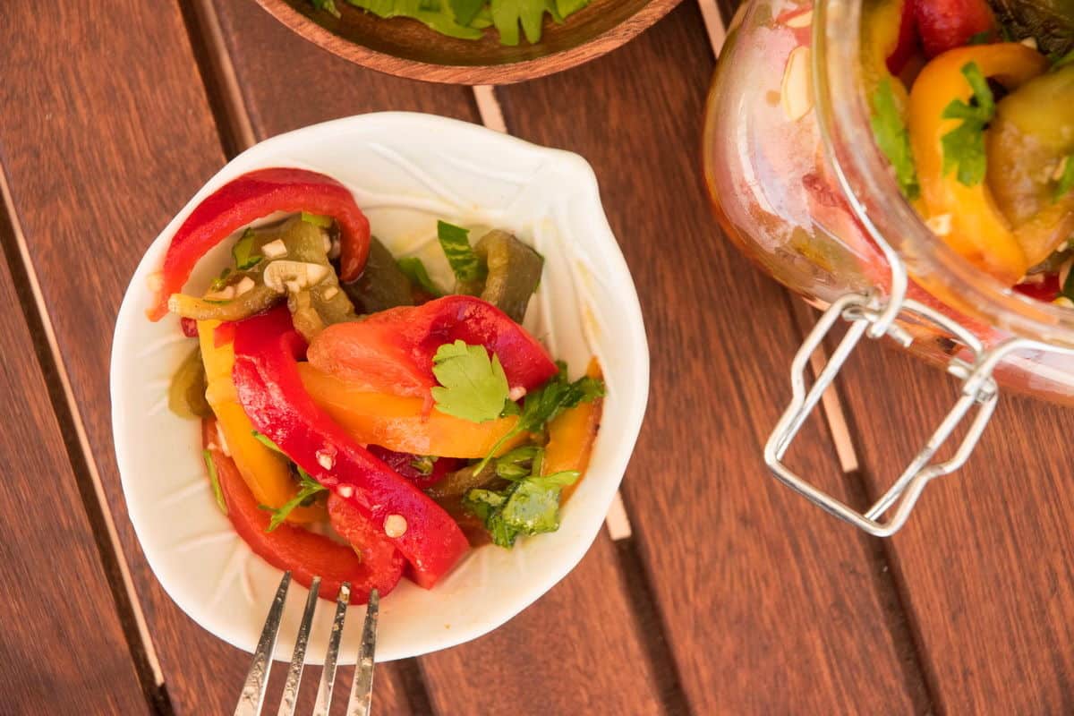 Grilled, sliced bell peppers in a bowl on wooden table.