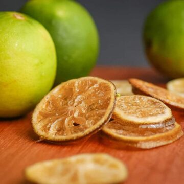 Sliced candied limes on wooden counter.