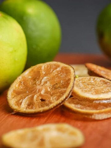 Sliced candied limes on wooden counter.