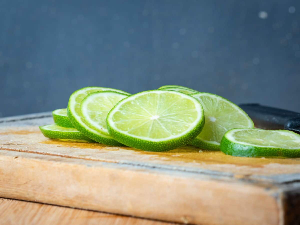 How to Candy Limes - Step 2 Lime slices on wooden cutting board.