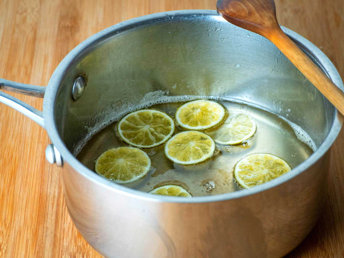 How to Candy Limes - Step 5 Candied limes in a pot with a wooden spoon, wooden background.