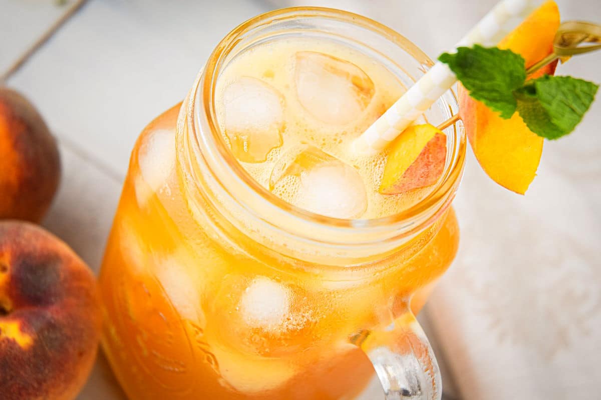 Iced Peach Green Tea in glass with peach wedge garnish.