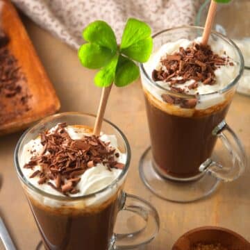 Irish coffee in coffee mug with 4 leaf clover, whipped cream and chocolate curls.