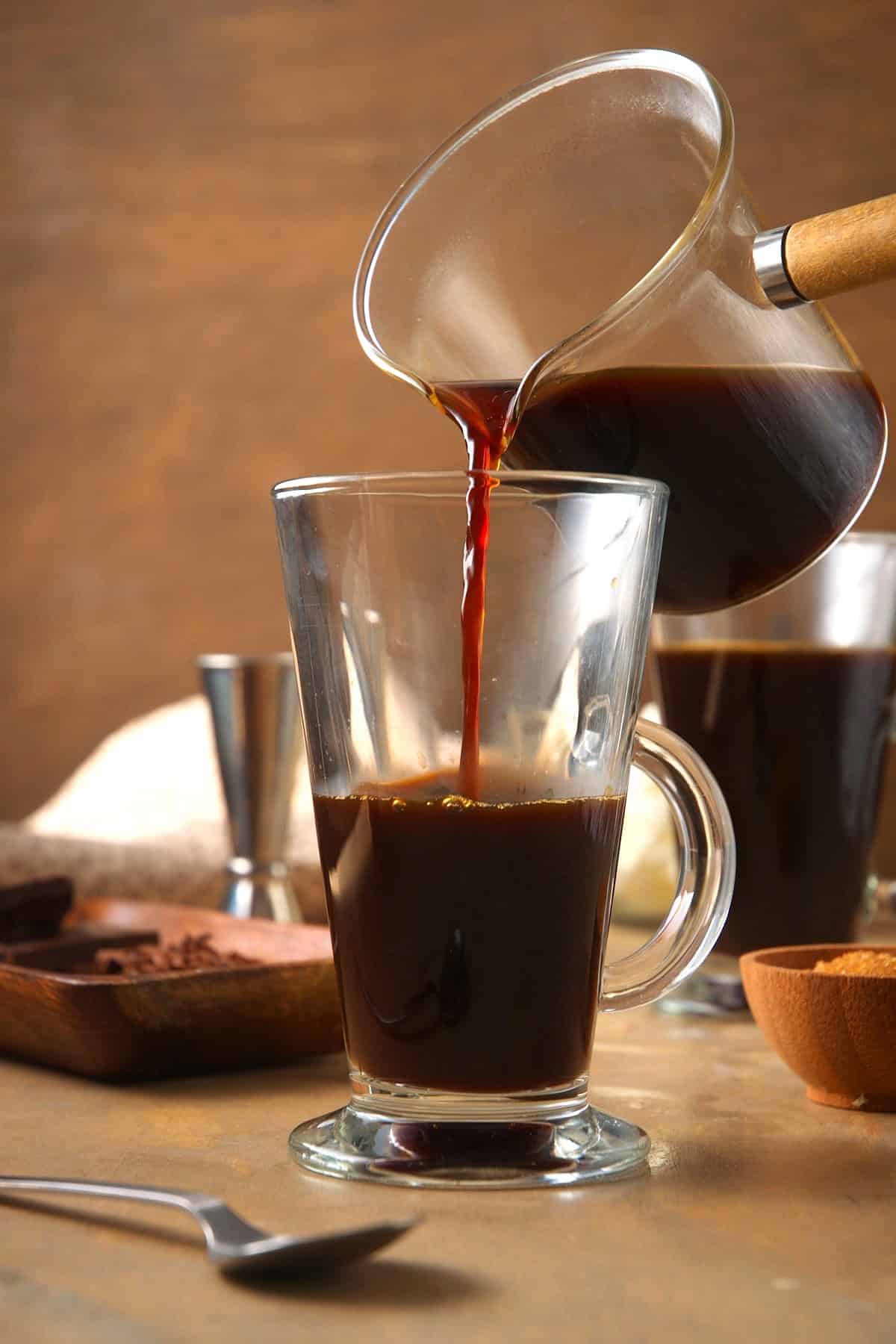 Hot coffee pouring into Irish coffee glass.