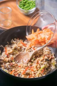 Kimchi bacon fried rice in frying pan with a wooden spoon.
