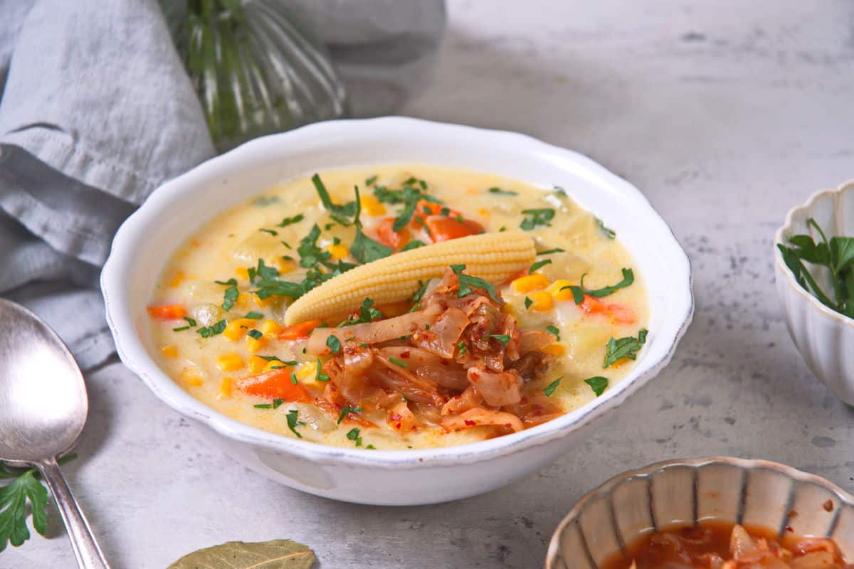 Kimchi chowder in a white bowl on light marble background.