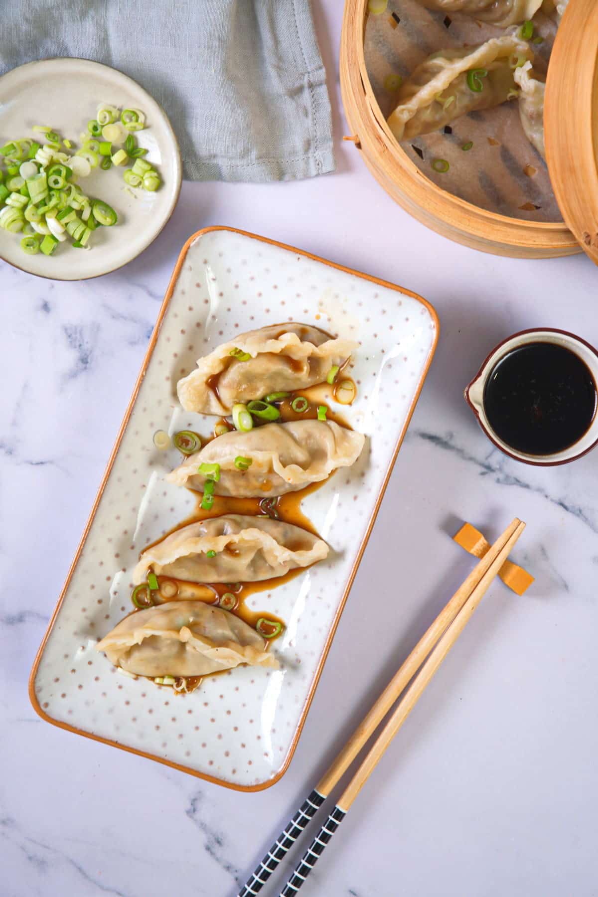 A tray of kimchi dumplings with chopsticks and Asian dipping sauce on the side.