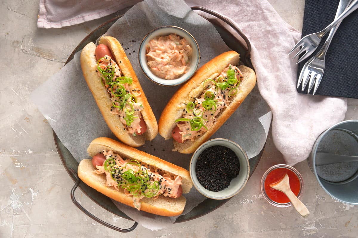Grilled hot dogs with kimchi topping and black sesame sides on the side.