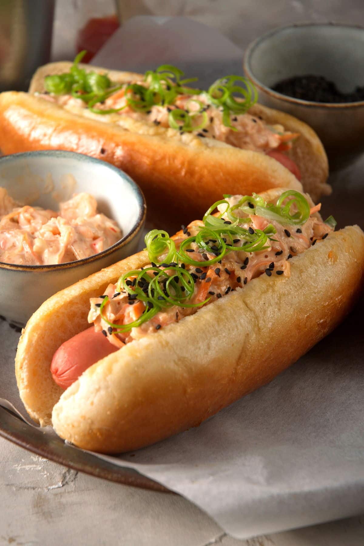 Hot dogs with creamy, kimchi topping, black sesame seeds and sliced green onions.
