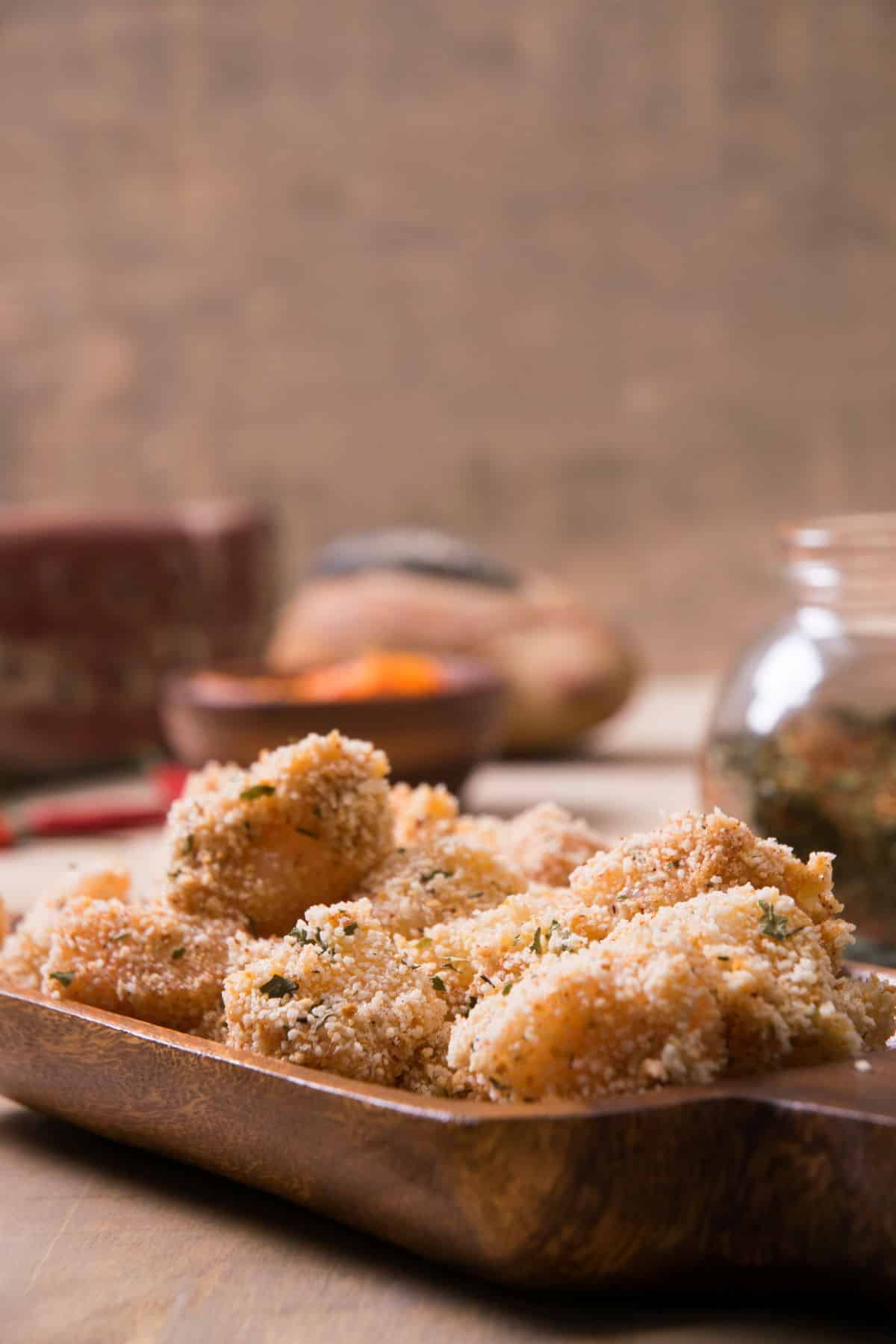 Raw, breaded cod in a wooden dish.