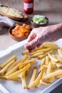 Frozen fries on a parchment-lined baking sheet.