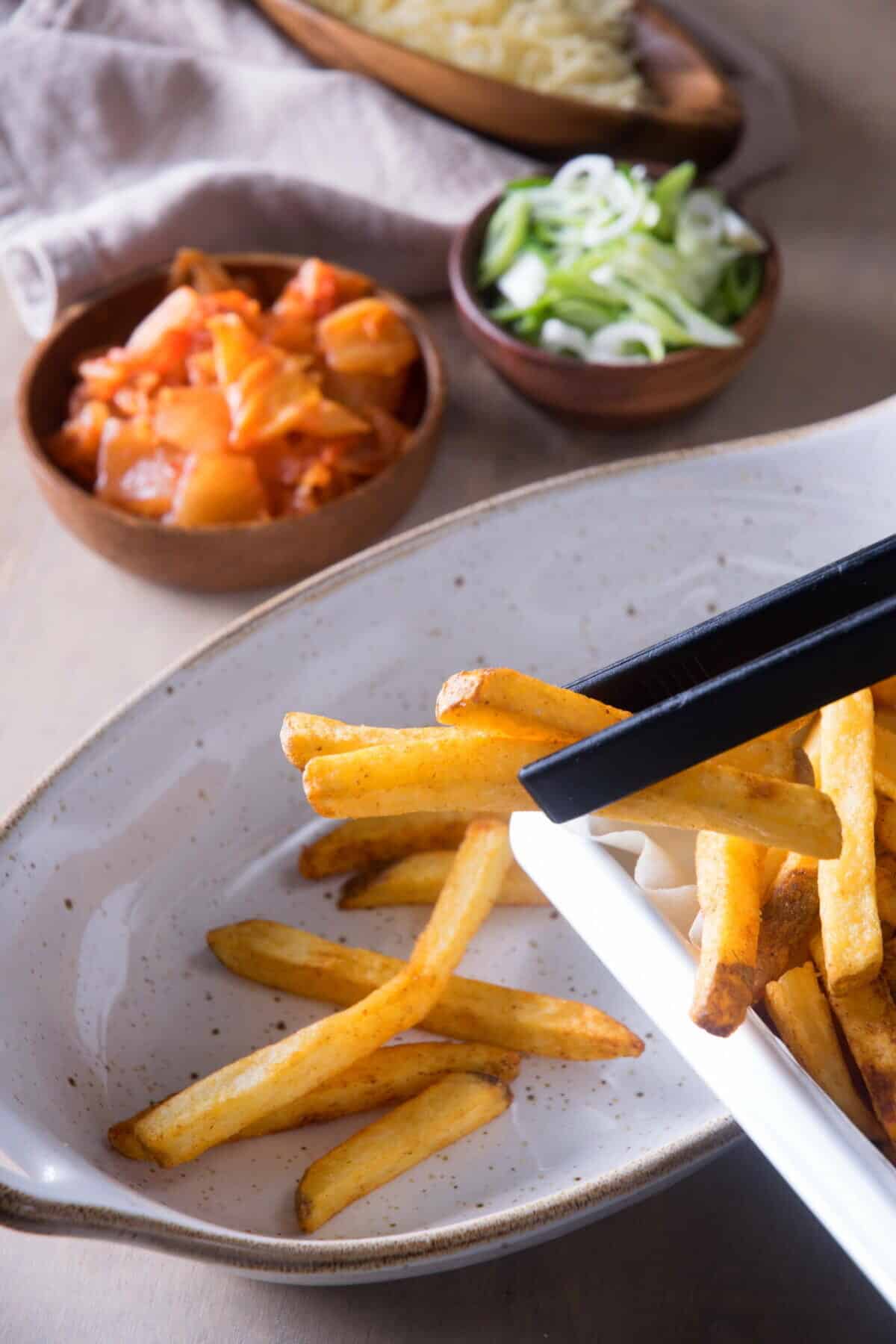 Fries in a casserole dish. Kimchi on the side in a small bowl.