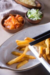 Fries in a casserole dish. Kimchi on the side in a small bowl.