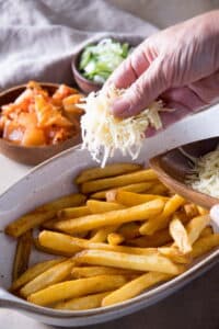 Fries in a casserole dish, kimchi topping on the side.